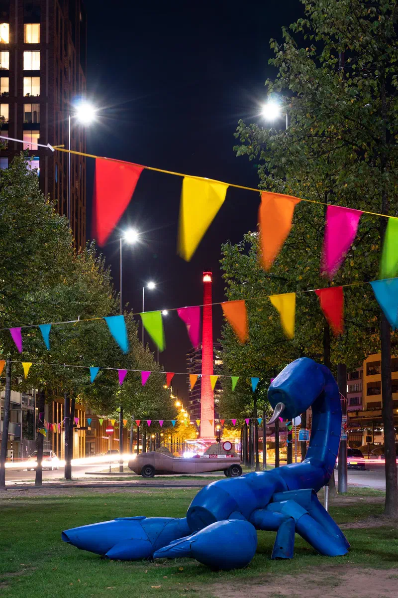 Giant blue scorpion sculpture in Strijp-S beneath colourful bunting at night