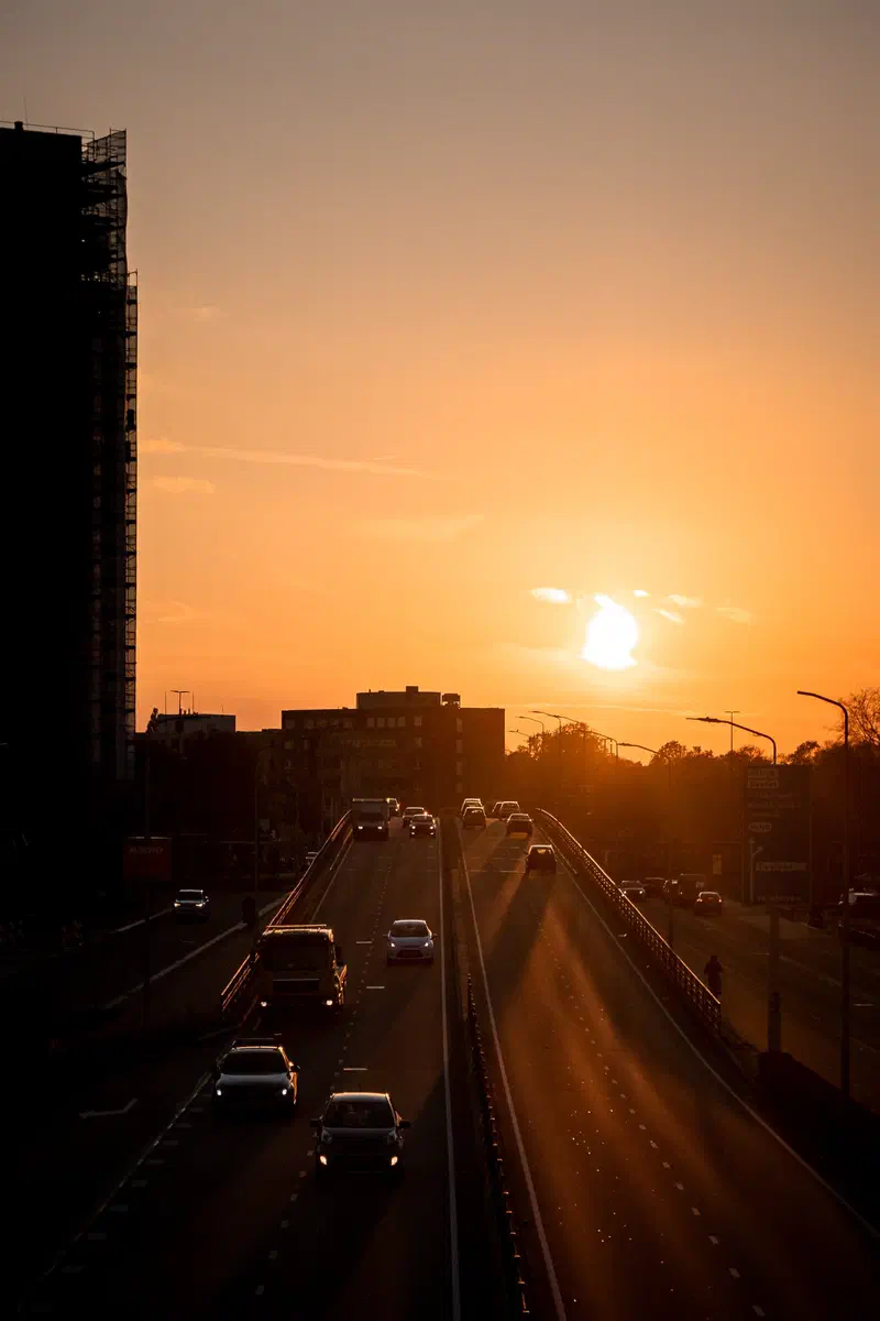 Sun setting over a busy road (Strijps Bultje) with silhouetted buildings (Strijp-S)