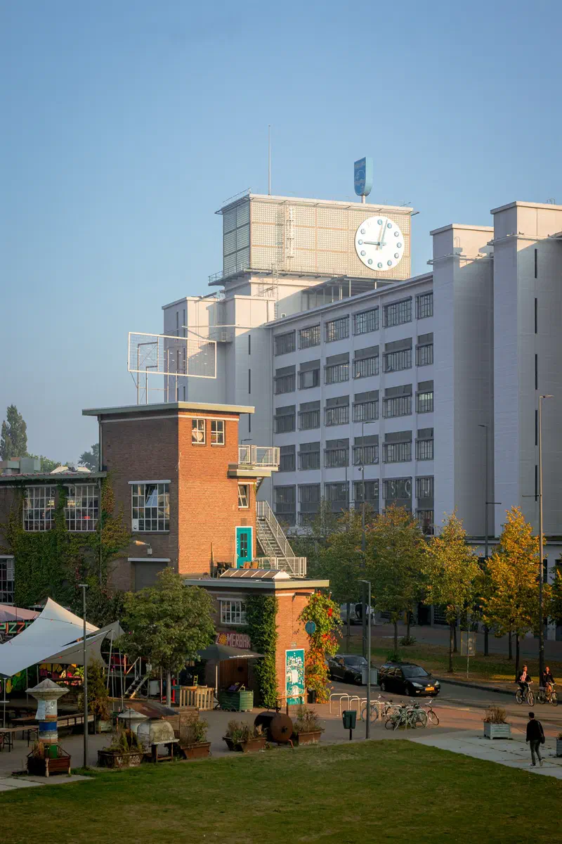 Former factory building (Klokgebouw) with a clock tower above a green park (Ketelhuisplein, Strijp-S) in autumn