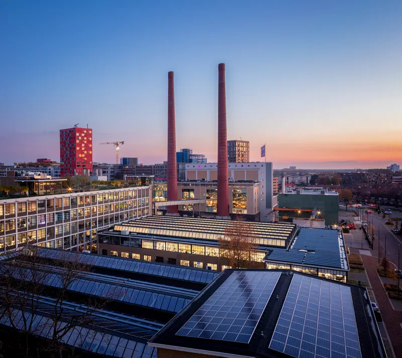 Twin chimneys (Strijp-T) and solar panel roofs of an industrial complex at sunset