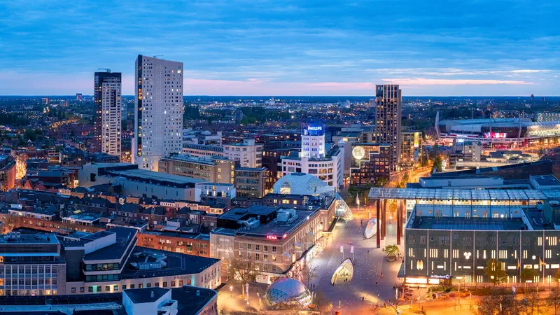 Blue-hour aerial view of the city centre with towers (Regent, Admirant, Lichttoren) and lit streets (18 Septemberplein)