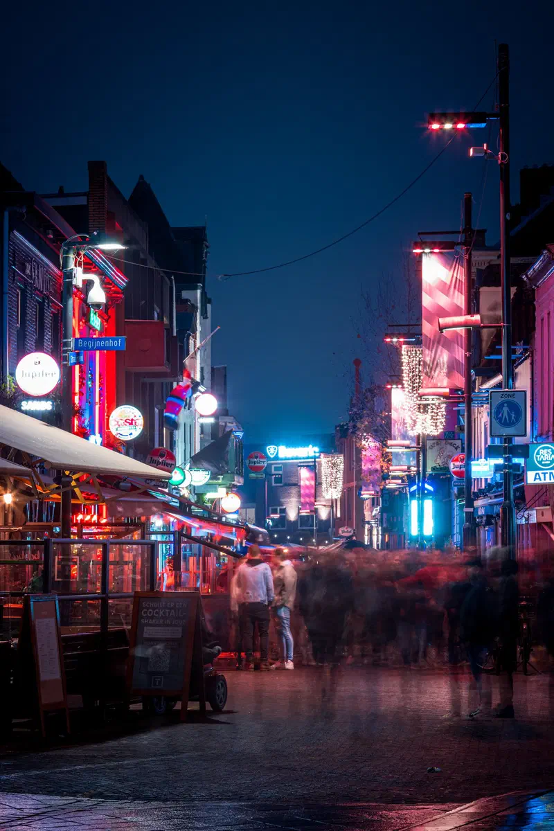 Neon-lit café street (Stratumseind) at night with blurred figures