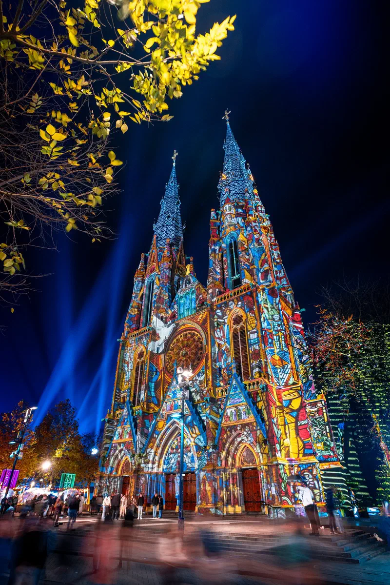 Sint-Catharinakerk facade lit with colourful projections and blue light beams (Glow)