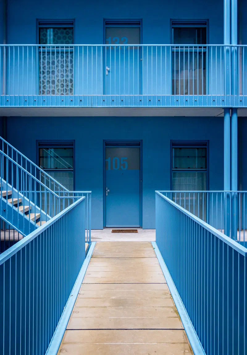 Blue apartment block (Strijp-S) with a straight walkway leading to a blue door