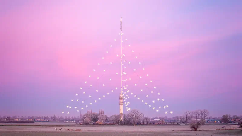 Gerbrandytoren lit as a Christmas tree under a pink winter sky
