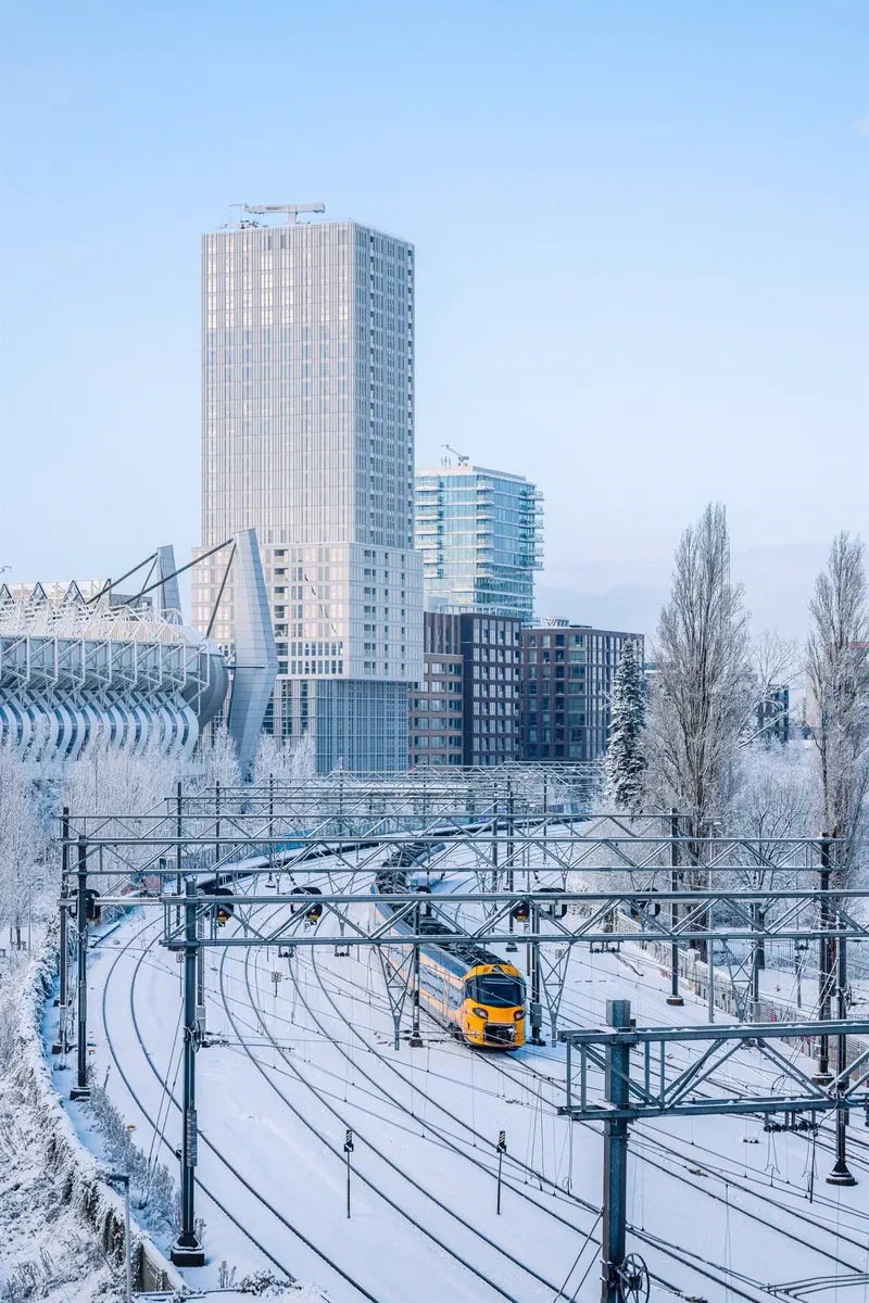 Train on snowy tracks beside the Philips Stadion and a tall tower