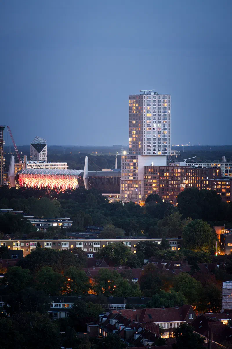 Eindhoven skyline at blue hour from Philips Nederland, with the lit Philips Stadion roof and a tall apartment tower