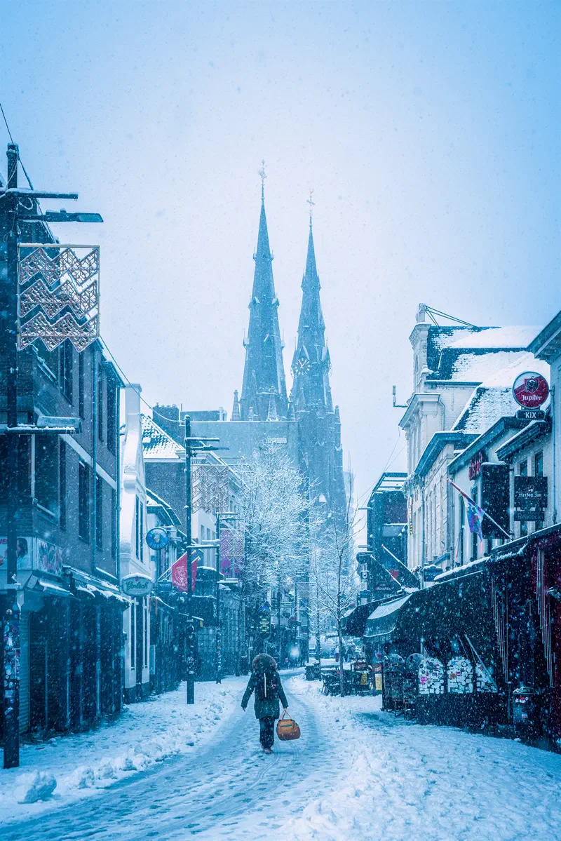 Person walking through a snowy café street (Stratumseind) toward Sint-Catharinakerk