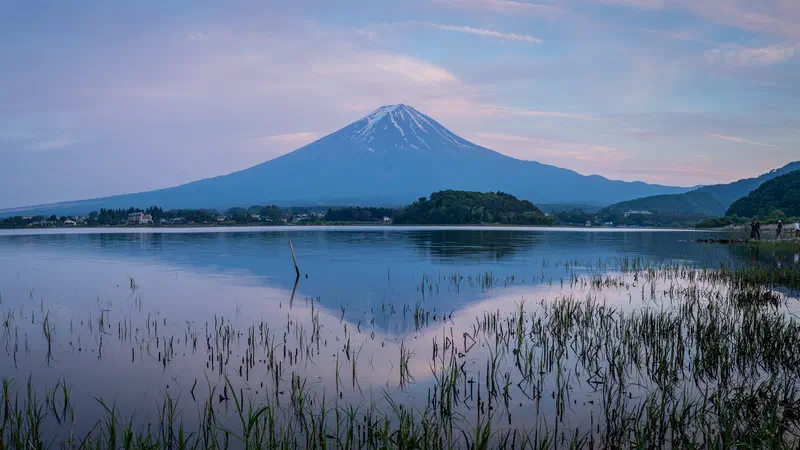 Snow-capped Mount Fuji across a still lake at dusk