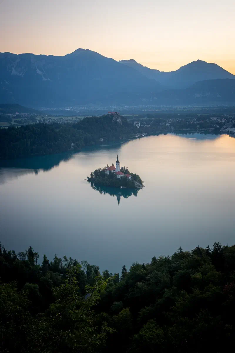 Lake Bled's island church with mountains beyond at dawn, Slovenia